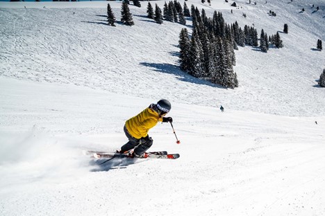 person in green jacket riding on red ski board on snow covered ground during daytime